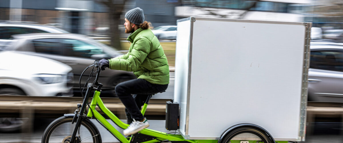 Bicycle courier delivering parcels in the city on a cargo bike