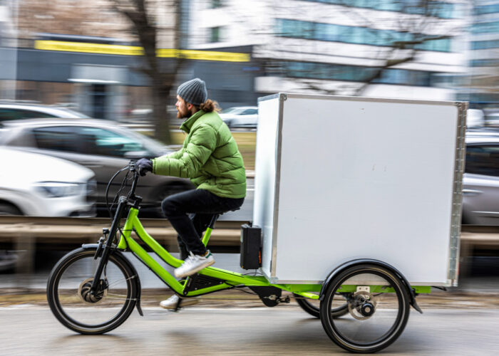 Bicycle courier delivering parcels in the city on a cargo bike
